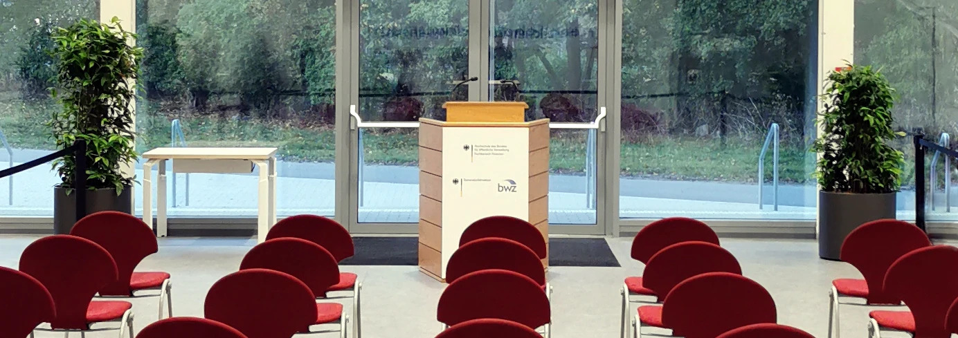 Rednerpult und leere Stühle vor einer Glasfront